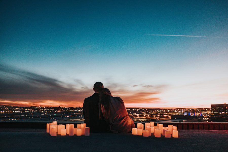 Couple watching sunset with candles on rooftop.