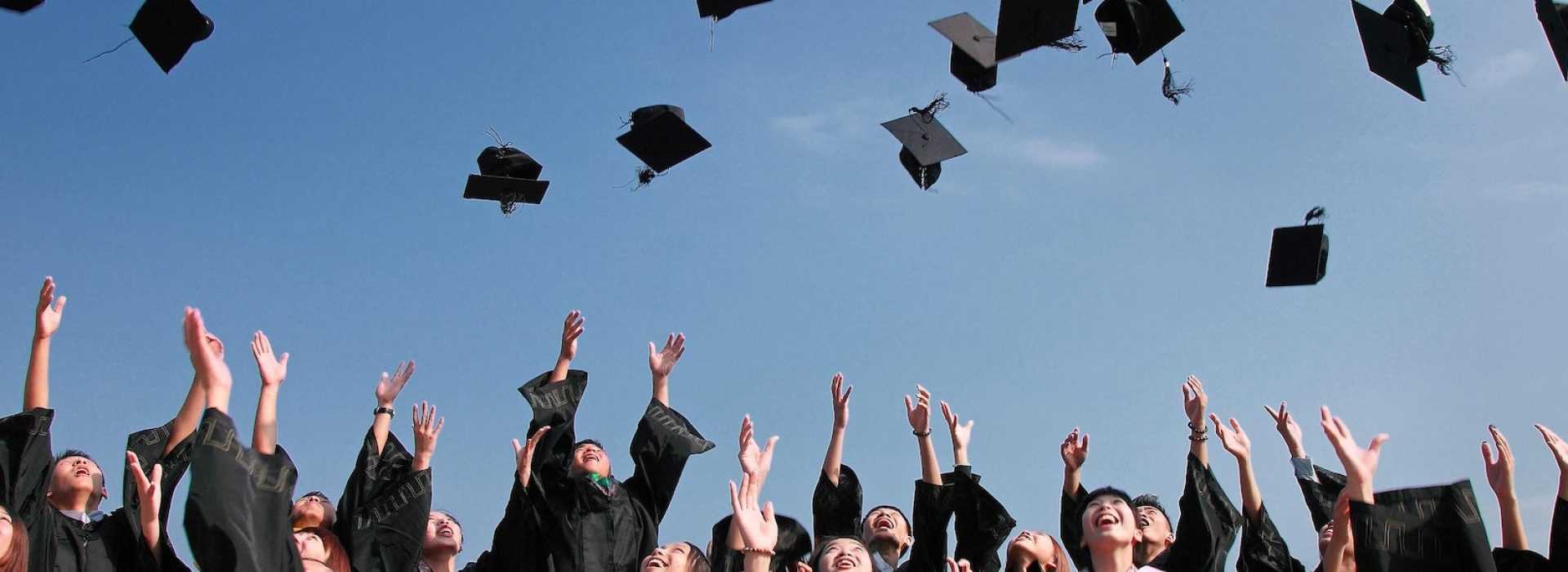 Graduates celebrating by tossing caps in the air.